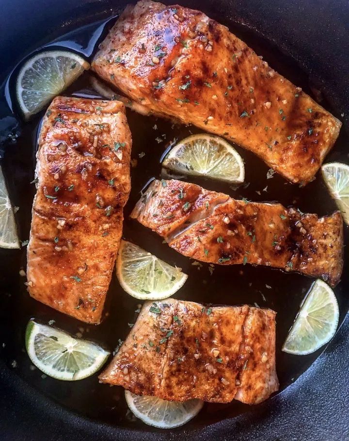 salmon and lemons in a skillet ready to be cooked on the stove top