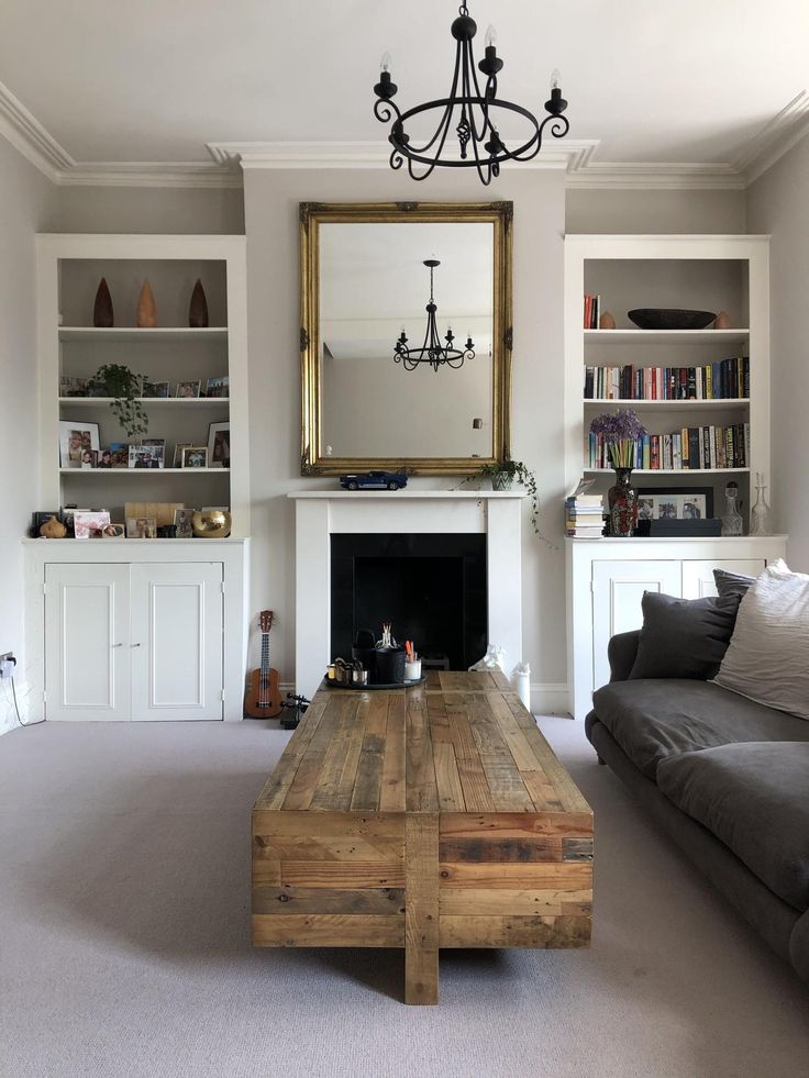 a living room with a couch, coffee table and bookshelves in front of a fireplace