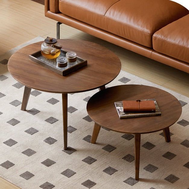 two coffee tables sitting on top of a rug in front of a brown leather couch