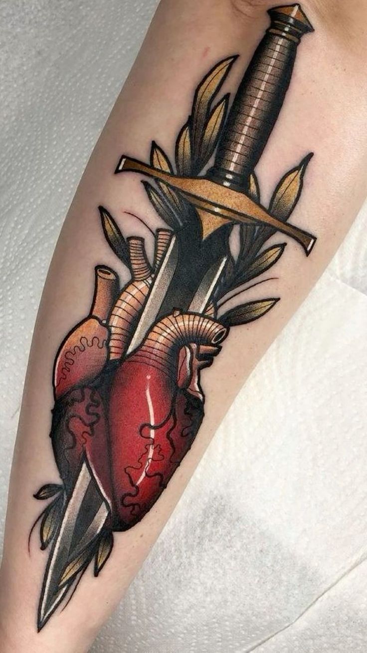 a heart and dagger tattoo on the right arm with an arrow sticking out of it