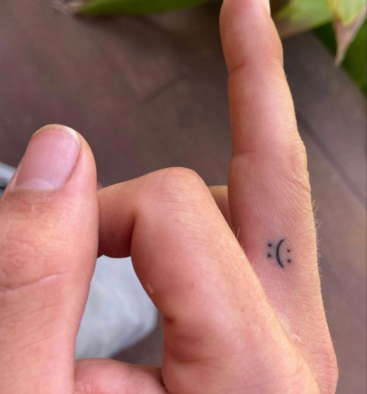 a person with a small tattoo on their left hand and fingers pointing to the right