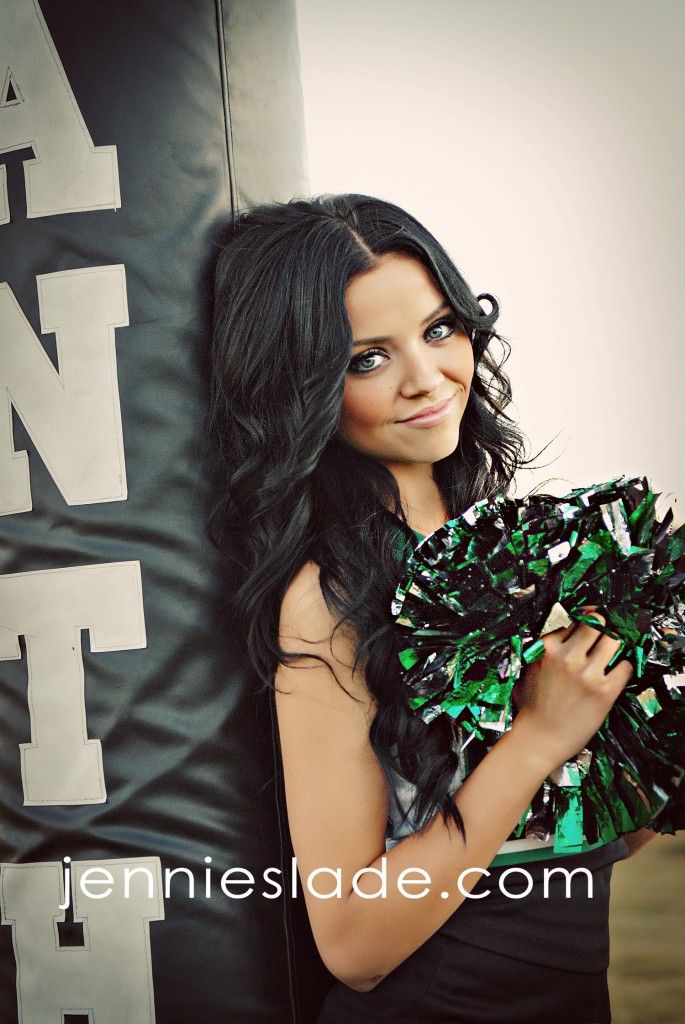 a beautiful young lady holding a cheerleader's pom - pom