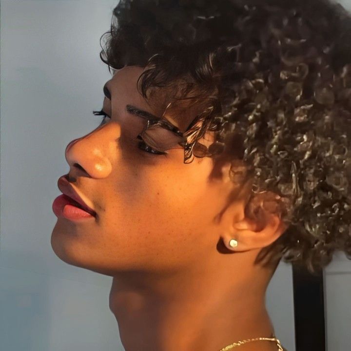 a close up of a person with curly hair wearing glasses and a necklace on her neck