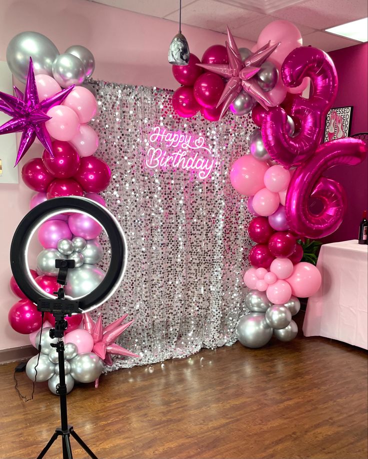 pink and silver balloons are on display in front of a backdrop