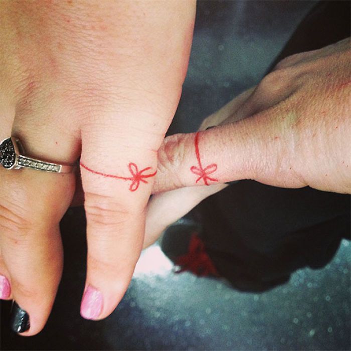 two people holding hands with tattoos on their fingers