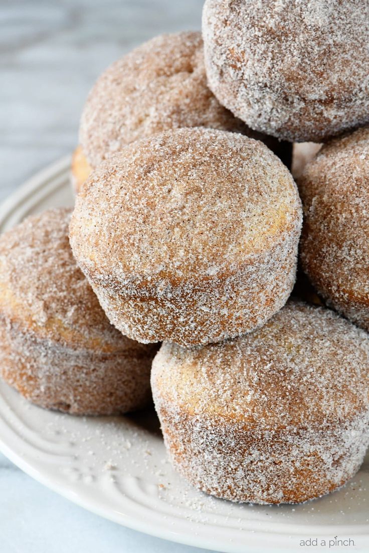 a pile of sugared doughnuts sitting on top of a white platter