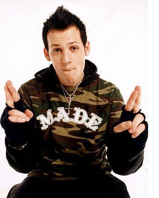 a man sitting on top of a chair wearing a camo hoodie and holding his hands in the air