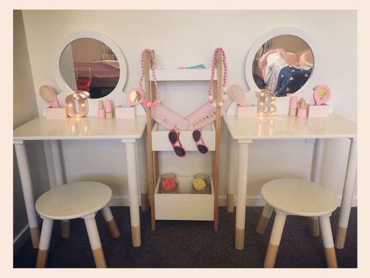 two vanity tables with stools and mirrors on top of them in front of a white wall