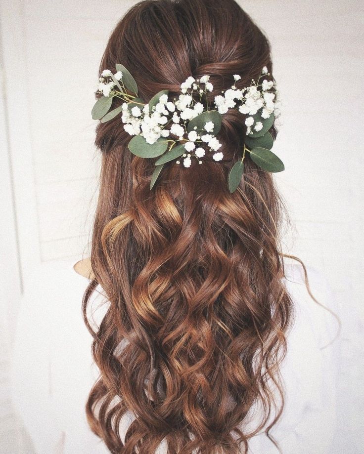 the back of a woman's head with long wavy hair and flowers in her hair