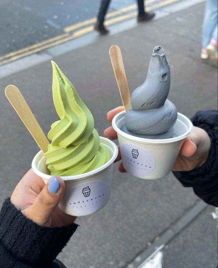 two people holding up cups with ice cream and bananas