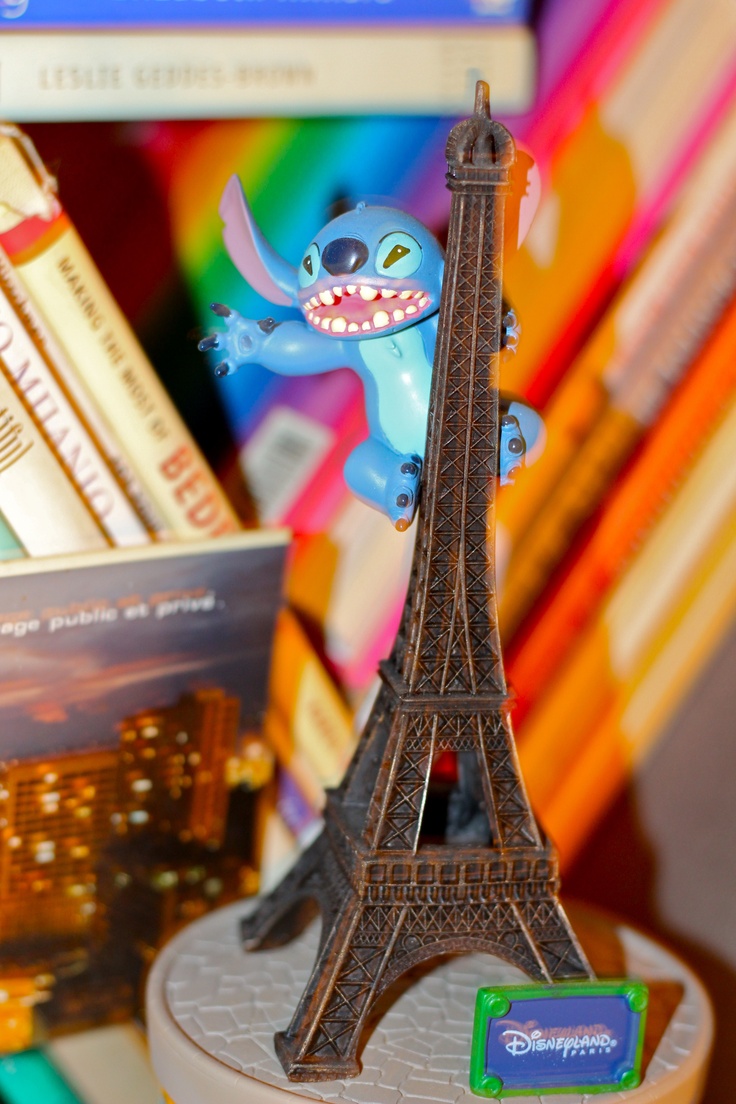 the toy is sitting on top of the book shelf in front of the eiffel tower