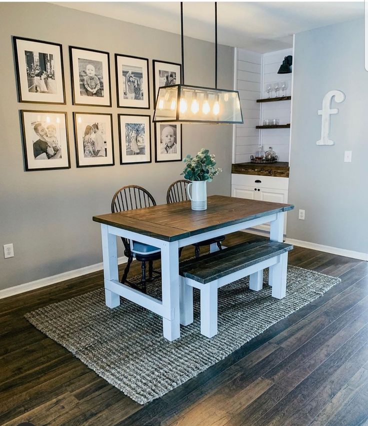 a dining room table and bench with pictures on the wall