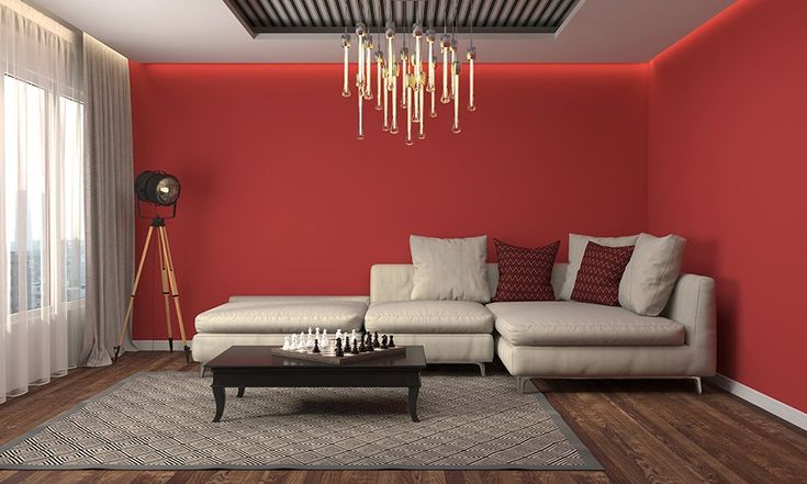 a living room with red walls, white furniture and a chandelier hanging from the ceiling