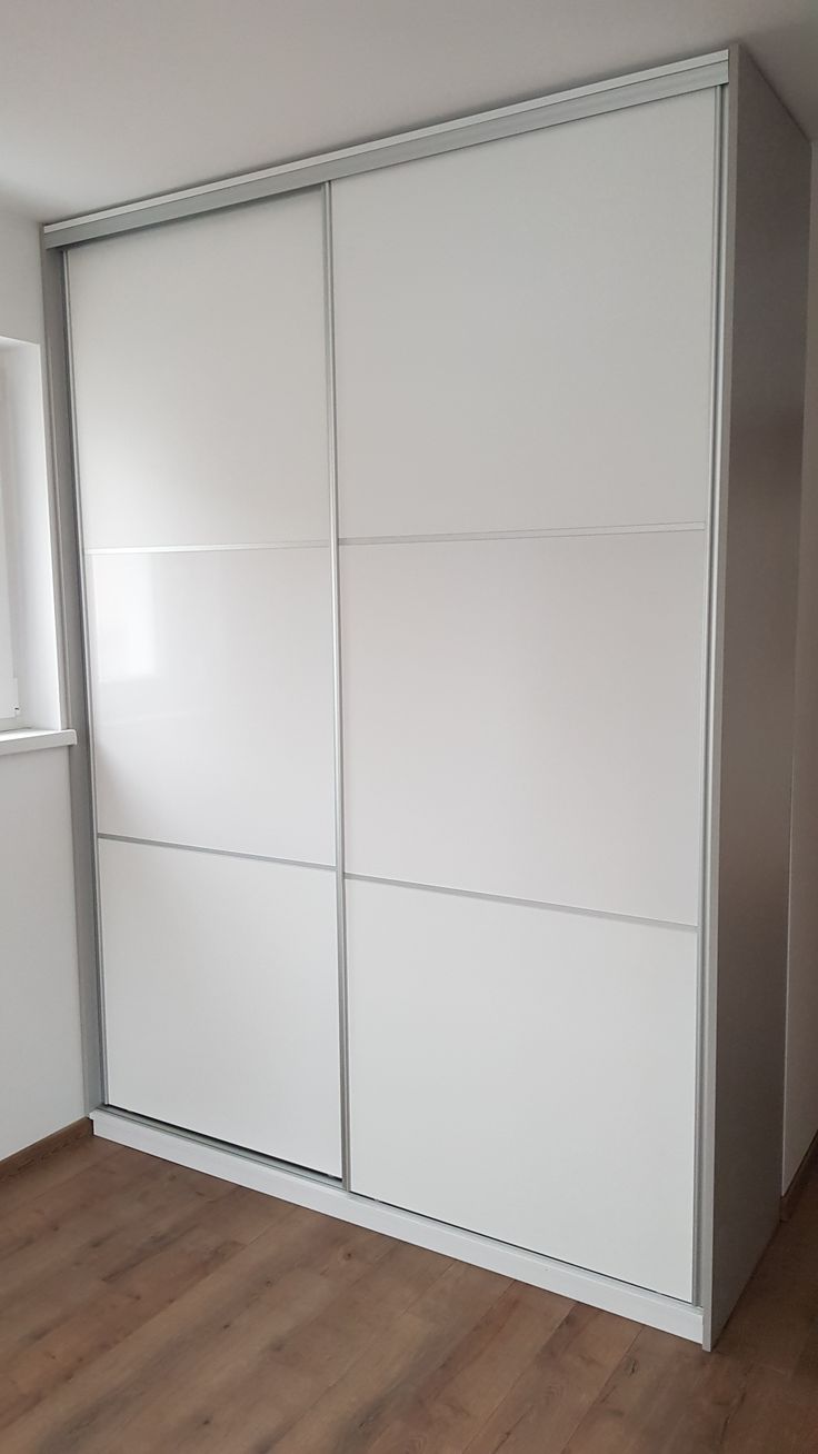 an empty room with white closet doors and hard wood flooring