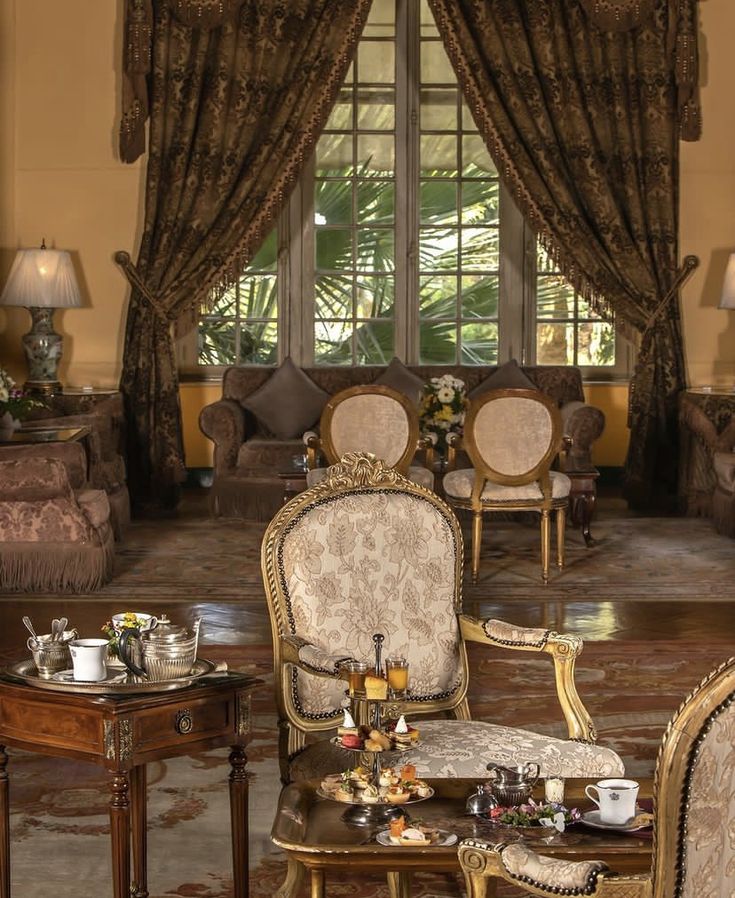 a living room filled with lots of furniture next to a large window covered in curtains