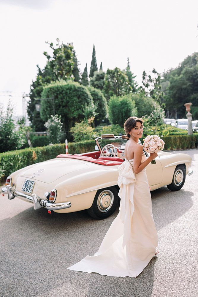 a woman in a wedding dress standing next to a car