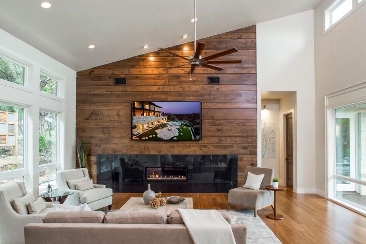 a living room with two couches and a television mounted on the wall above it