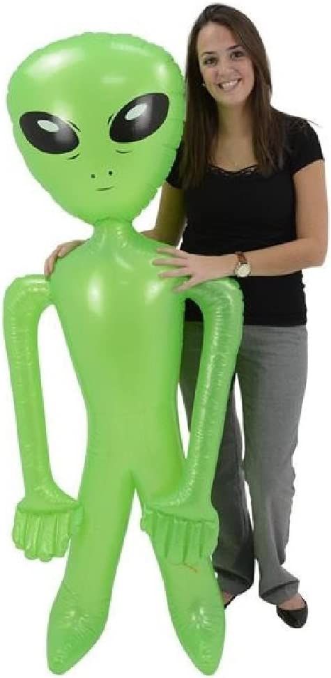 a woman standing next to an inflatable green alien balloon with eyes on it