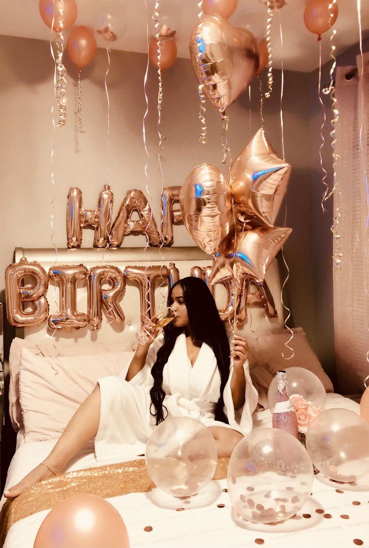 a woman sitting on top of a bed surrounded by balloons