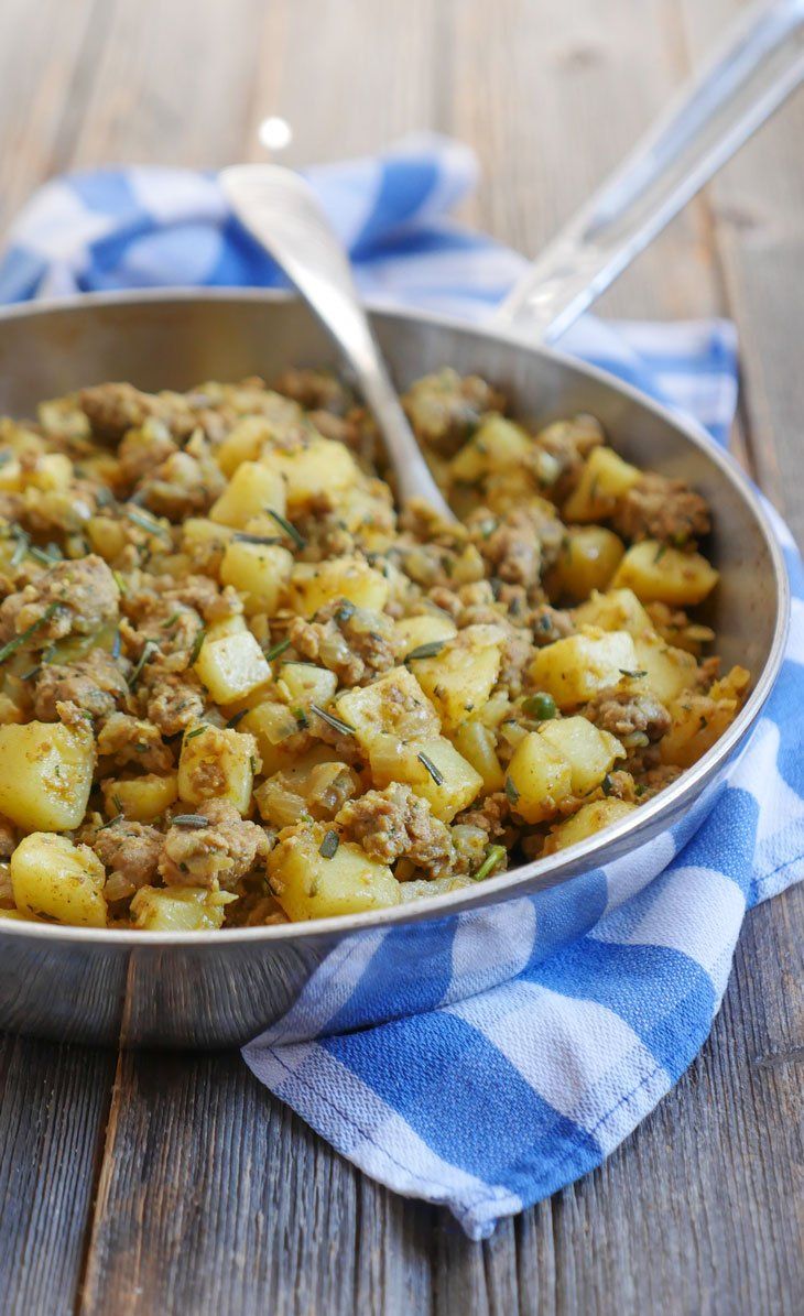 a pan filled with potatoes on top of a blue and white checkered towel next to a spoon