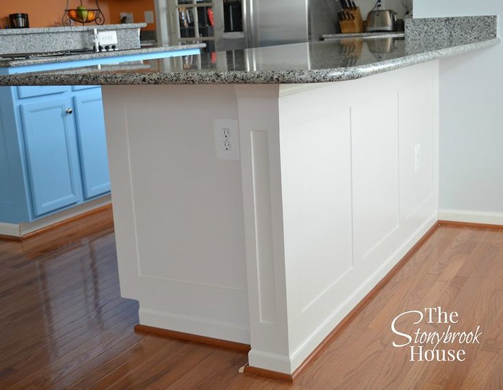 an island in the middle of a kitchen with stainless steel appliances and blue cabinetry