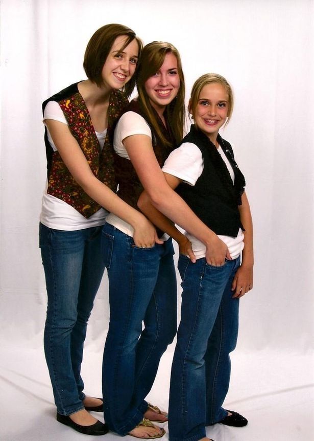 three young women are posing for a photo together in front of a white background and one is holding her arms around the other woman's back