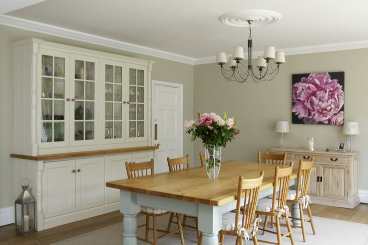 a dining room table surrounded by chairs and vases with flowers in the center on top