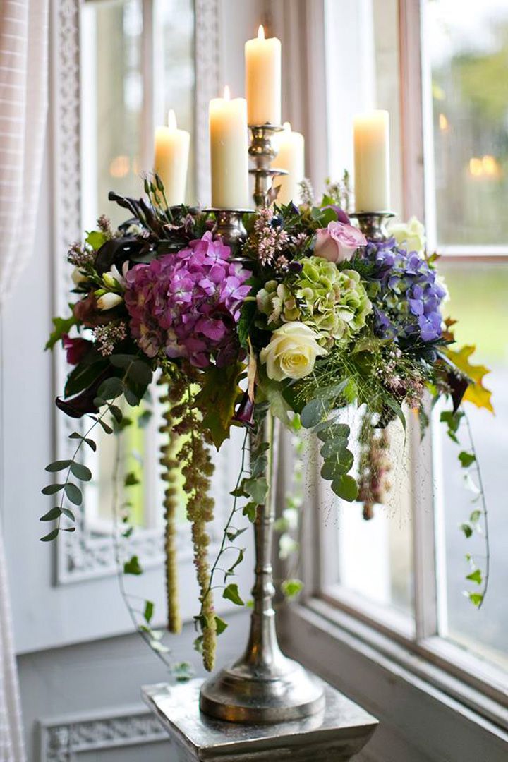 a vase filled with flowers and candles on top of a table