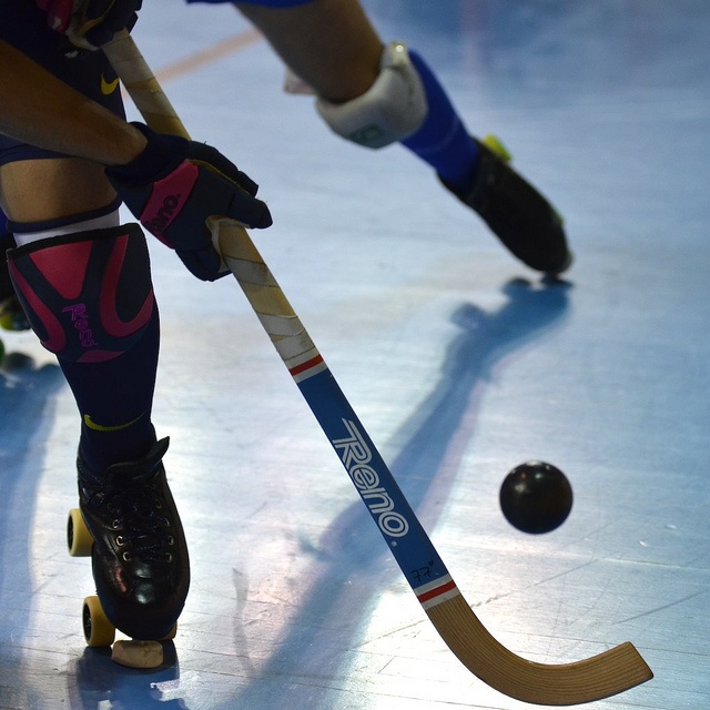 the legs and feet of two hockey players in blue uniforms playing ice hockey on an indoor rink