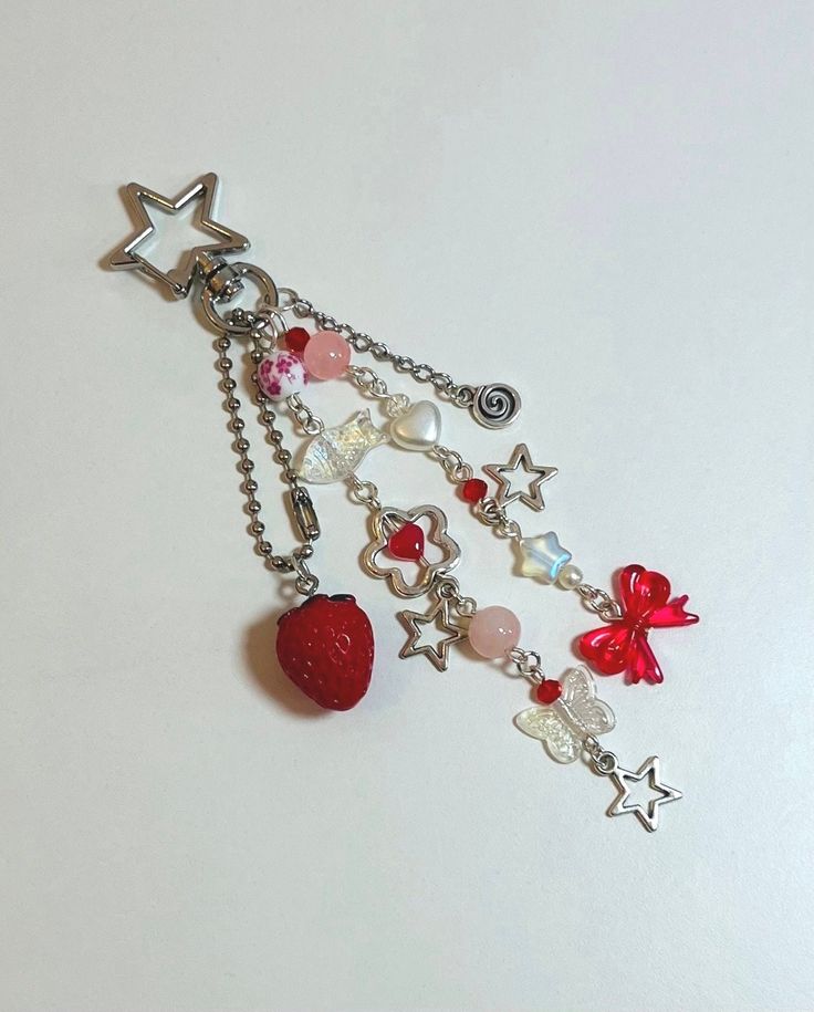 a close up of a chain with charms on it and a strawberry hanging from the end