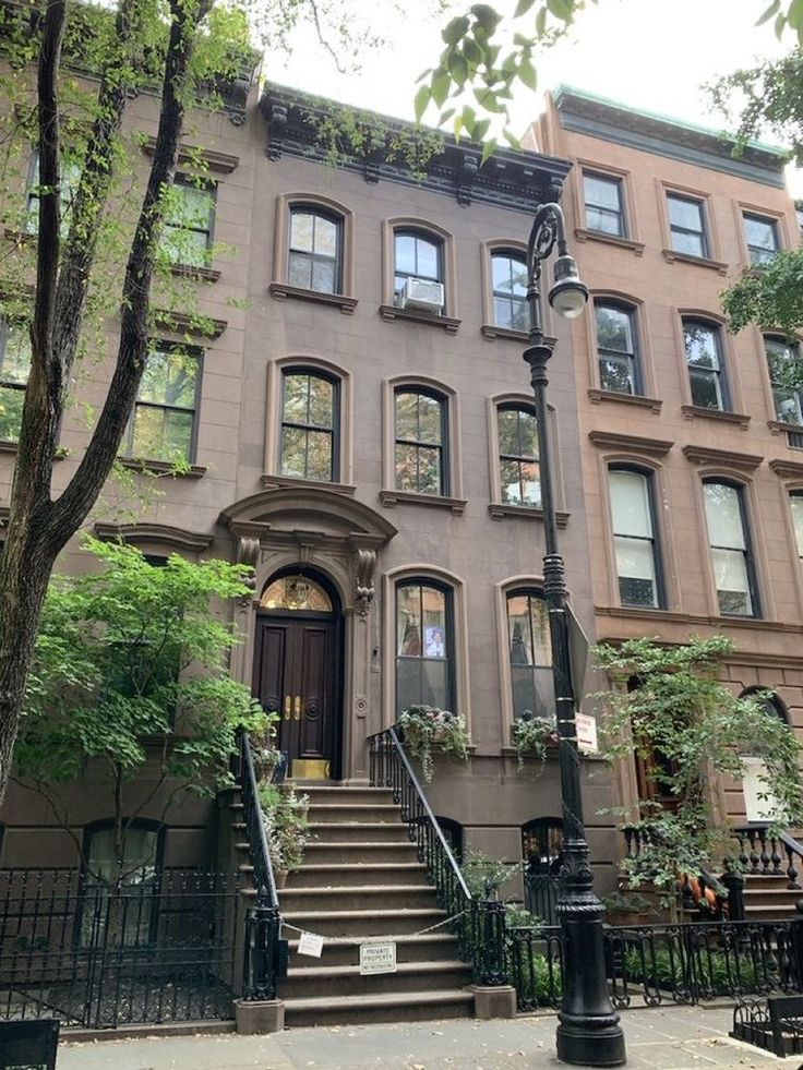 an apartment building with stairs leading up to the front door and second story windows on one side