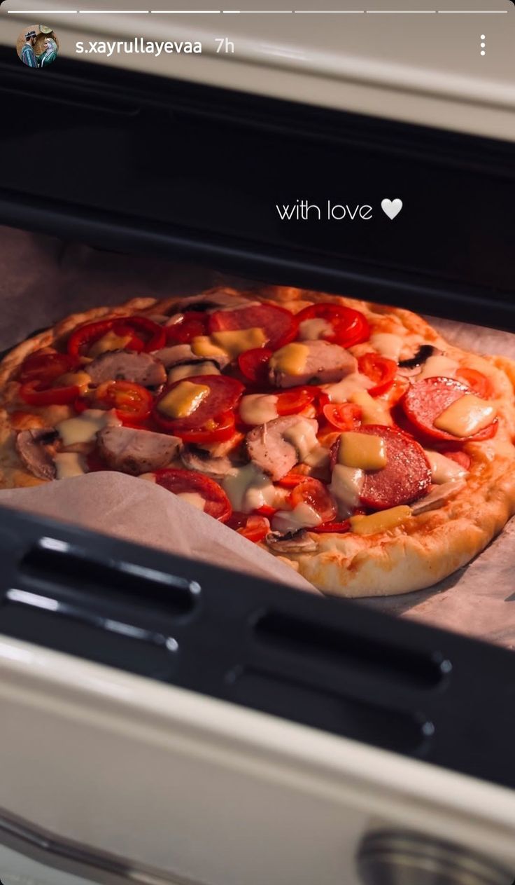 a pizza sitting inside of an oven on top of parchment paper in front of it