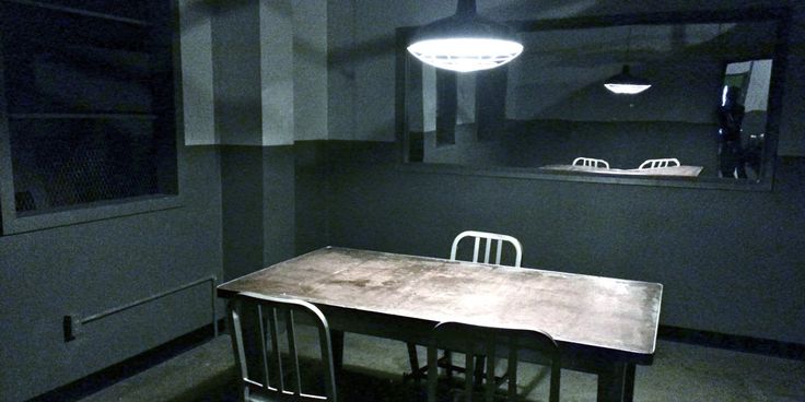 a table and chairs in a dark room with lights hanging from the ceiling above it