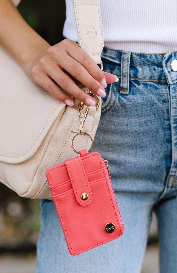 a woman holding a pink purse with a chain attached to it's side pocket