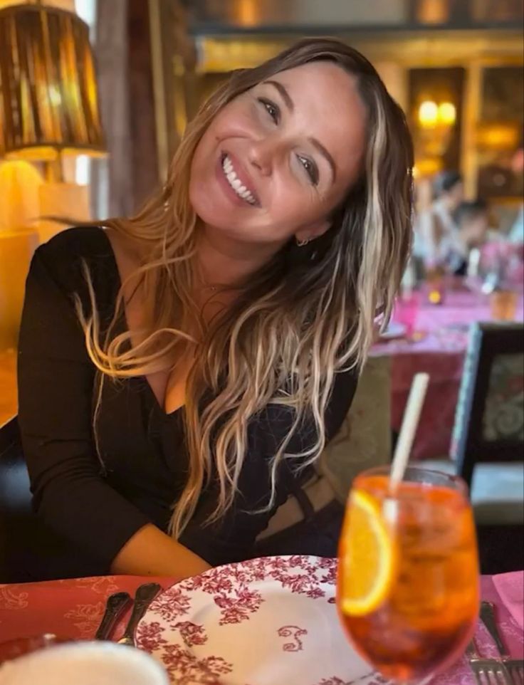 a woman sitting at a table with an orange slice in front of her