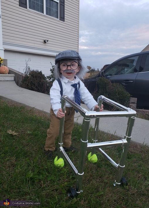 a small child dressed as an old man with tennis balls