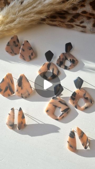 several pieces of animal print jewelry sitting on a table next to a feather and some scissors