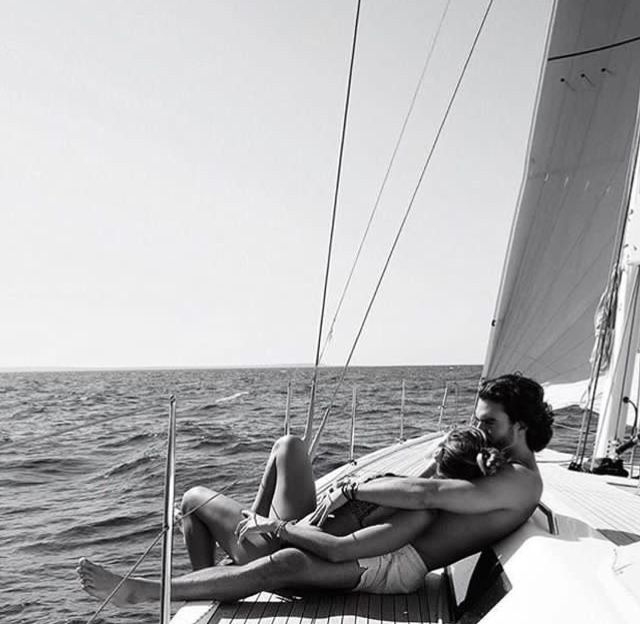 two people are relaxing on the deck of a sailboat