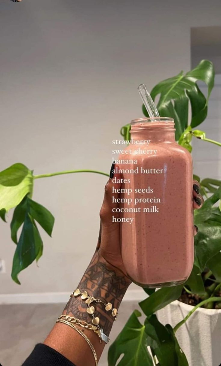 a person holding a pink smoothie in a mason jar with a quote on it