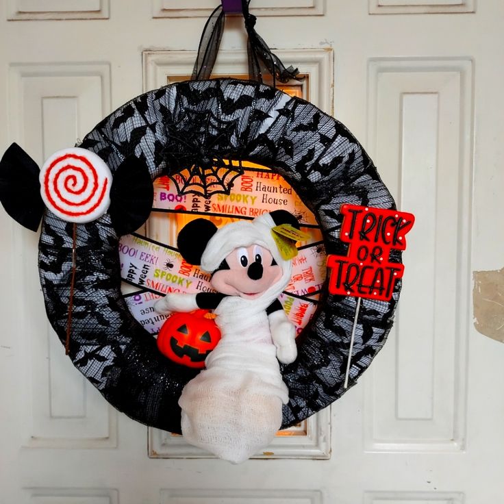 a mickey mouse wreath hanging on the front door with candy and lollipops