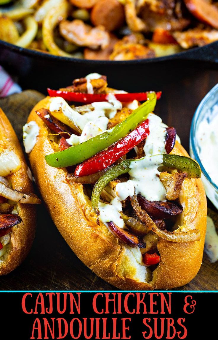 two hot dogs on buns with peppers, onions and ranch dressing in the background