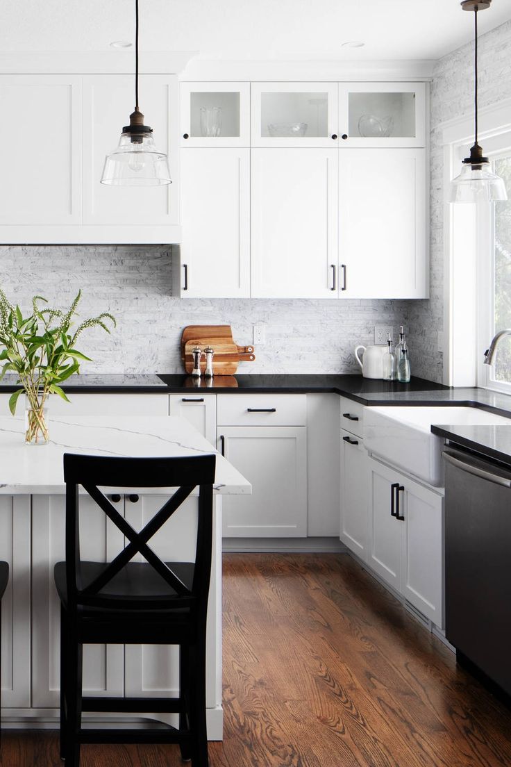 a kitchen with white cabinets and black chairs