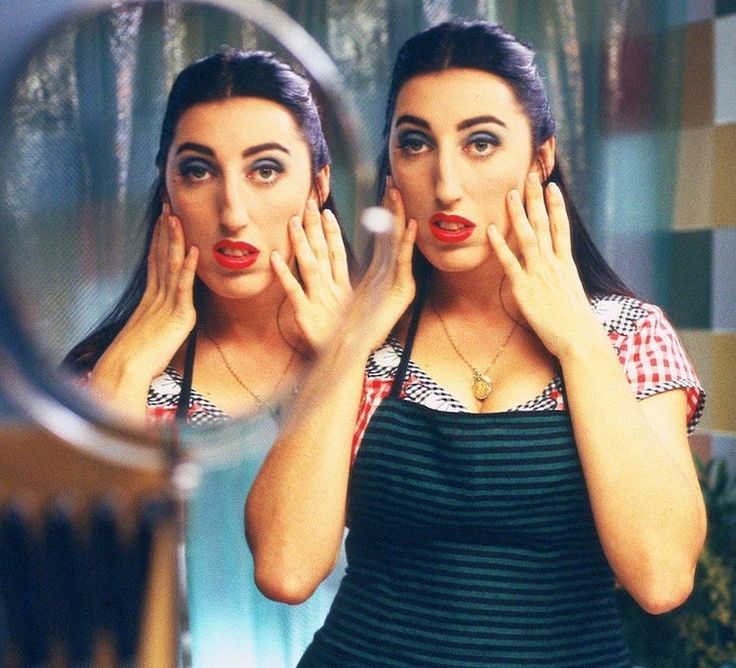 a woman with her hands on her face in front of a mirror