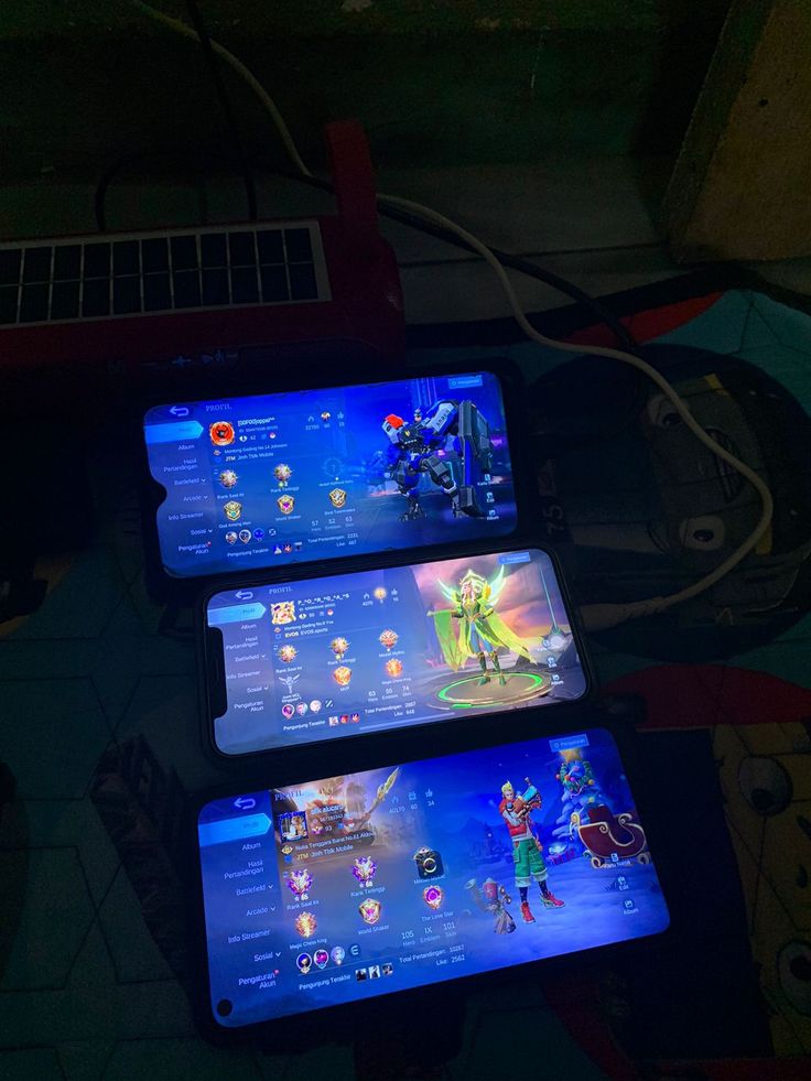 three cell phones sitting next to each other on top of a table in the dark