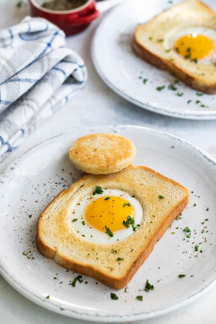 two slices of toast with an egg in the middle on them, sitting on a white plate