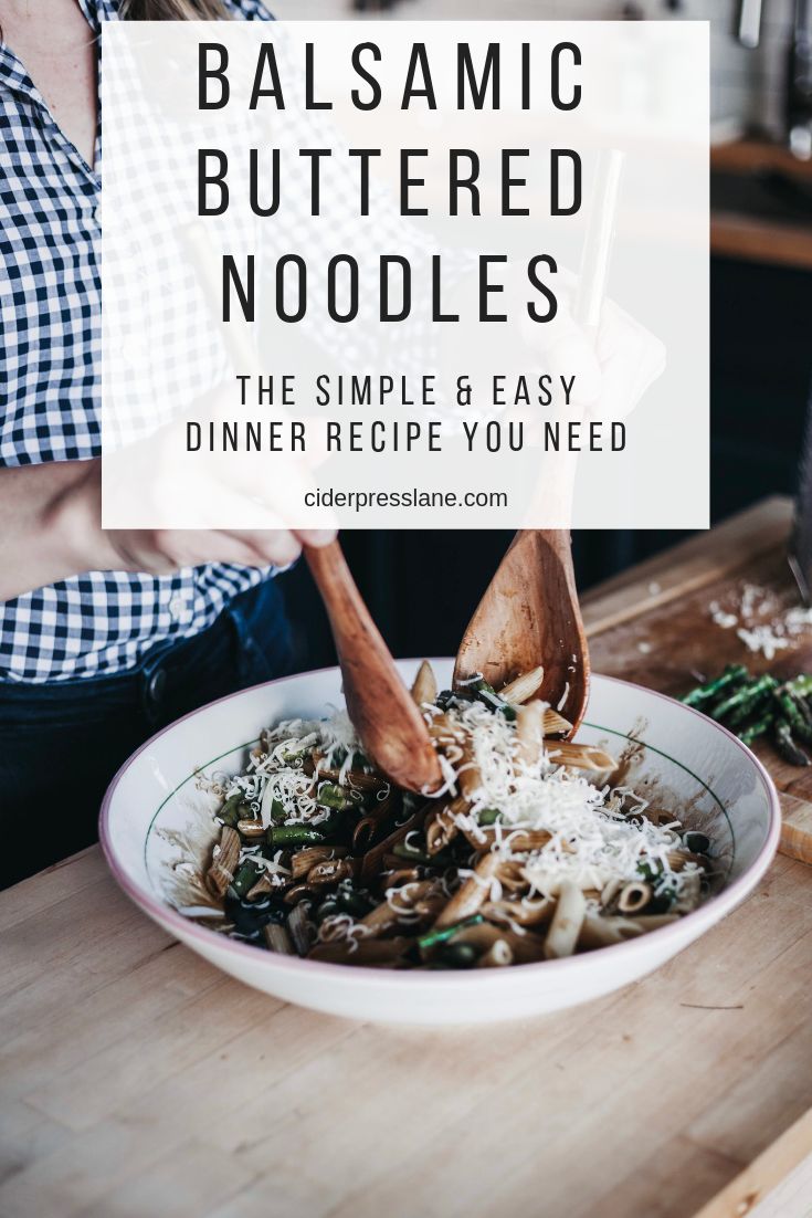 a bowl filled with pasta and mushrooms on top of a wooden table next to a woman