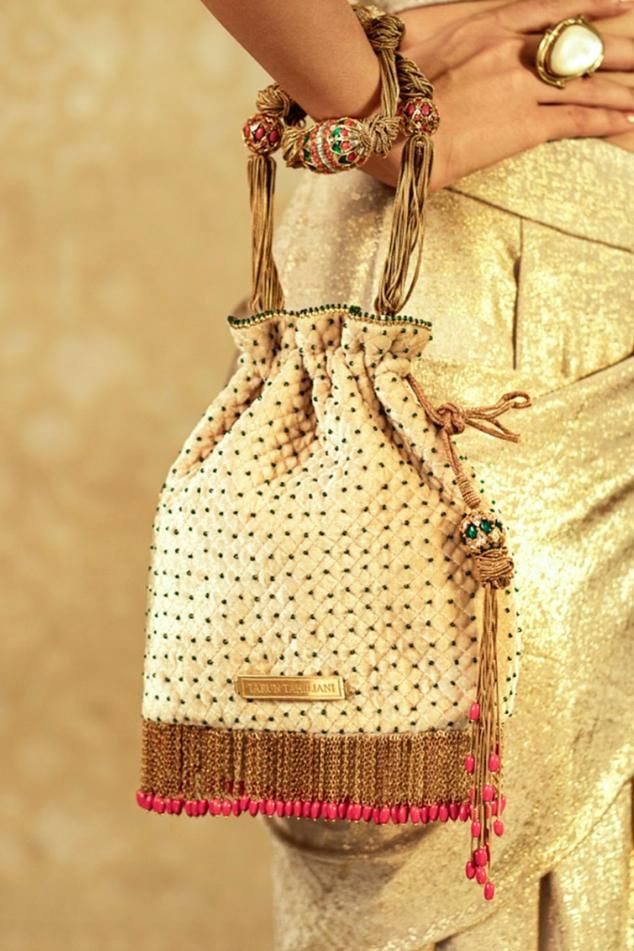 Ivory soft body potli bag, studded all-over, with metallic fringes and coloured beads. With chain and jewelled beaded handle with semi-precious stones dipped in 24K gold. - Aza Fashions Luxury Tassels Traditional Dupatta, Luxury Traditional Choli With Tassels, Luxury Festive Choli With Tassels, Luxury Choli With Latkans For Festivals, Luxury Dupatta With Pallu For Festivals, Luxury Festival Dupatta With Pallu, Luxury Dupatta For Rituals And Festivals, Luxury Dupatta With Tassels For Festivals, Luxury Tassel Sets For Eid