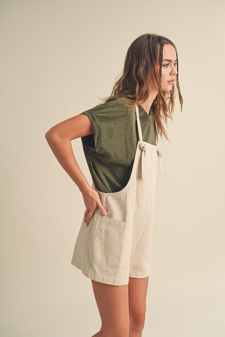 This "Harbor" romper flaunts effortless, relaxed style. Its tied sleeves and large pockets offer comfort and convenience. Crafted from lightweight, breathable fabric, it's sure to be your go-to piece for easygoing days. Summer Shortalls With Pockets In Relaxed Fit, Summer Relaxed Fit Shortalls With Pockets, Relaxed Fit Summer Shortalls With Pockets, Summer Style Relaxed Fit Shortalls With Pockets, Summer Shortalls With Side Pockets And Relaxed Fit, Neutral Summer Jumpsuits And Rompers With Pockets, Summer Neutral Jumpsuits And Rompers With Pockets, Cream Jumpsuits And Rompers With Pockets For Summer, Summer Neutral-colored Jumpsuits And Rompers With Pockets