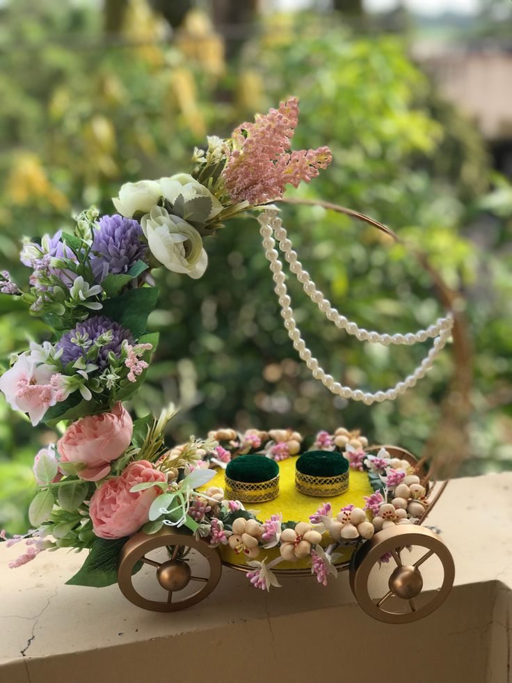 an old fashioned carriage with flowers and pearls on the wheels is sitting on a ledge