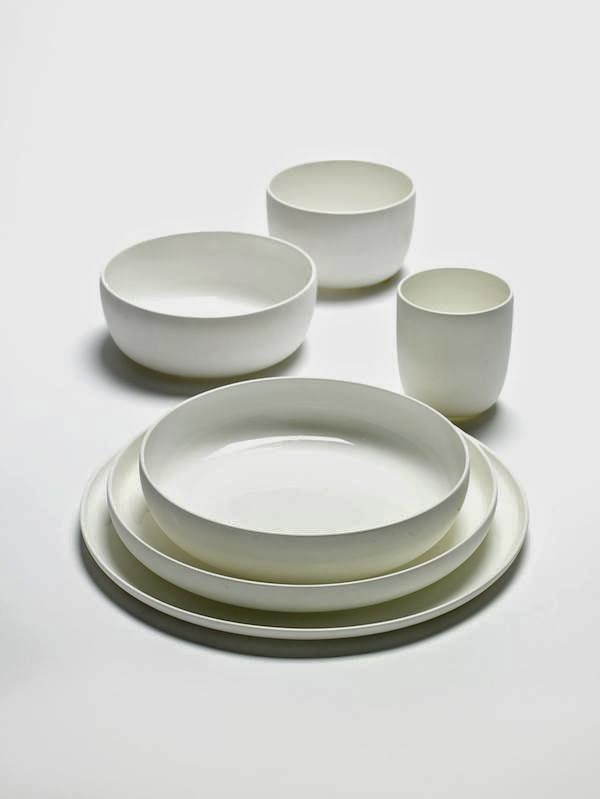 a white table setting with four plates and two cups on the top one is empty